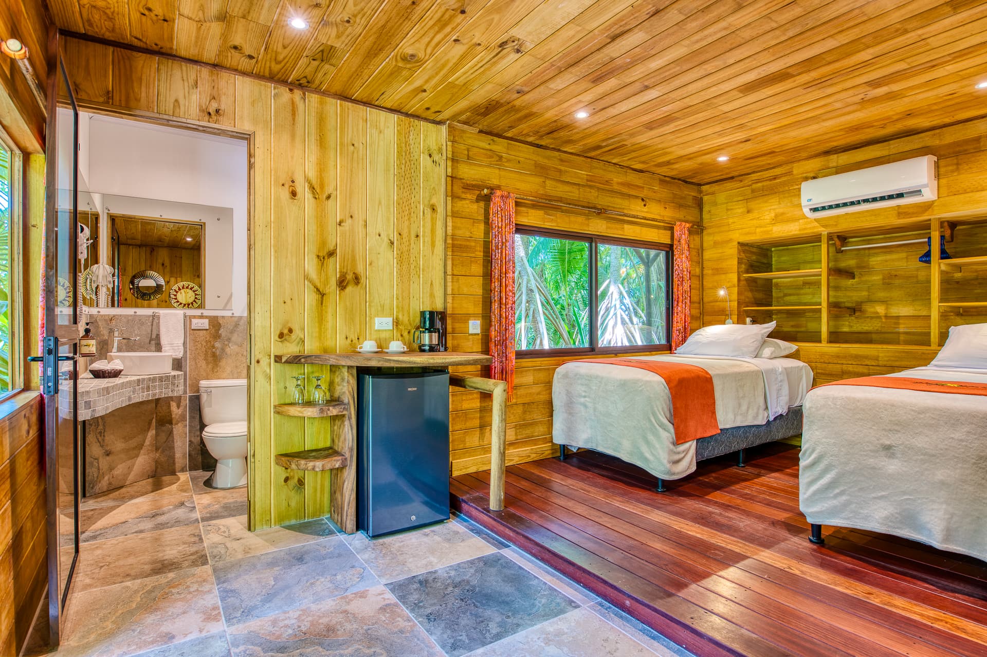 Cabina Room Interior with two beds, built-in shelves, mini fridge, and doorway into bathroom