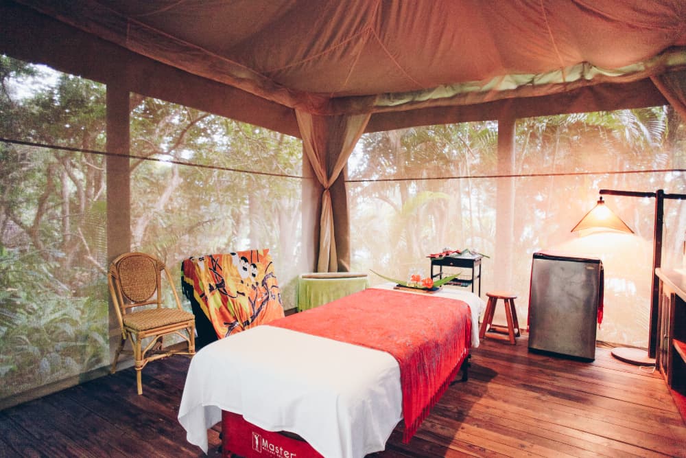 Screened cabana with massage table and surrounded by jungle