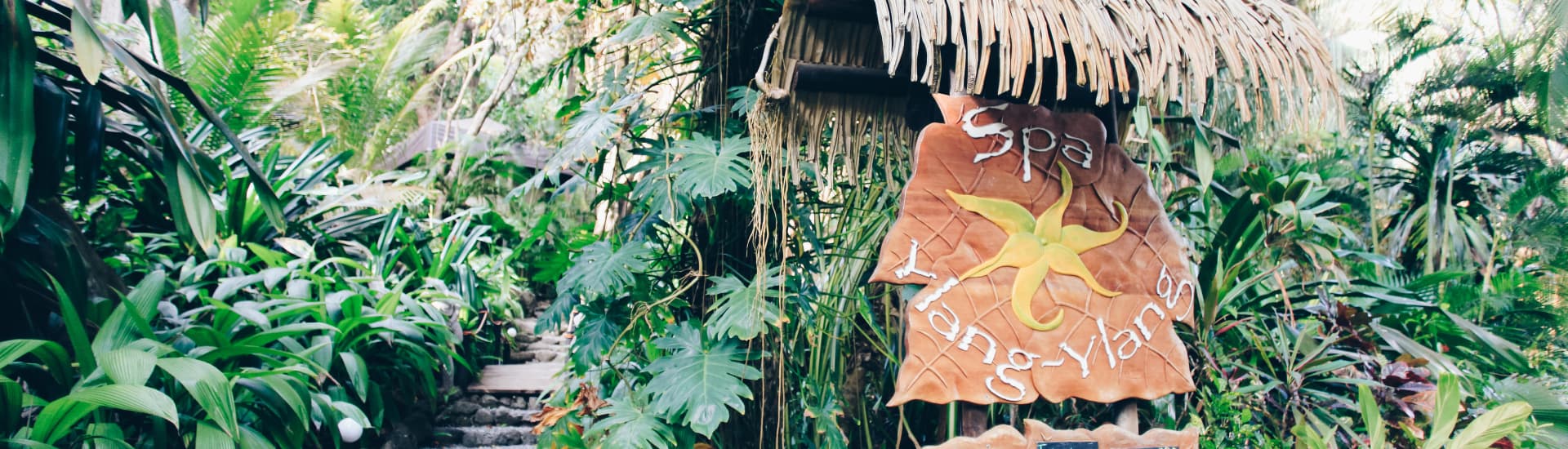 Sign for Ylang Ylang Spa at the entrance surrounded by lush tropical foliage