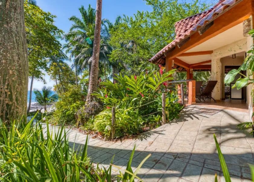 bungalow entrance with tiled walkway, lush greenery, and palm trees leading toward an ocean view bungalow entrance with tiled walkway, lush greenery, and palm trees leading toward an ocean view
