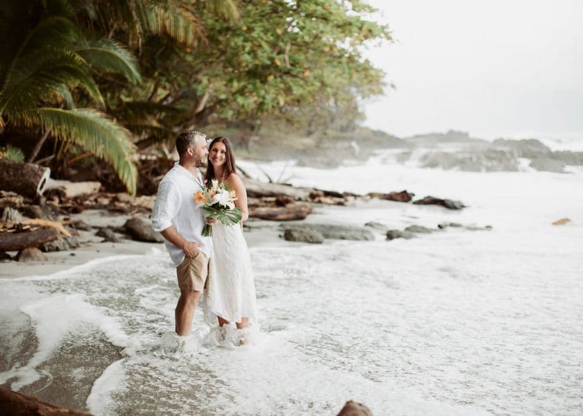 A couple stands together in the surf during a beach wedding portrait. A couple stands together in the surf during a beach wedding portrait.