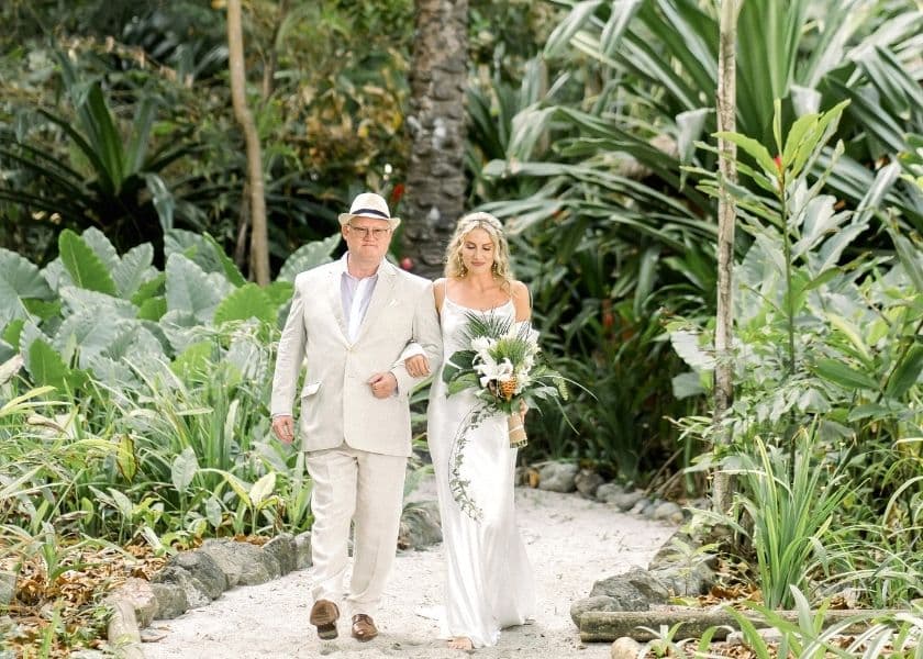bride walking down a tropical garden path with her father before a wedding ceremony bride walking down a tropical garden path with her father before a wedding ceremony